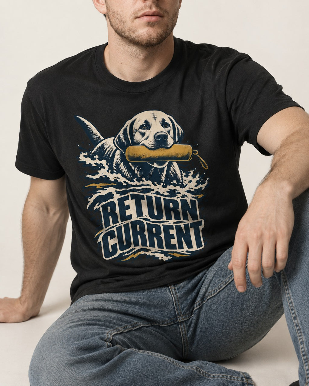 Return Current Water Retrieve Labrador Retriever Graphic T-Shirt in Black, worn by a seated model
