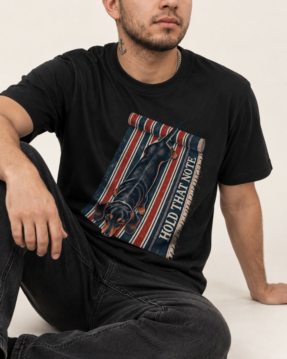 Dachshund Hold That Note Striped Rug Graphic T-Shirt in Black, worn by a seated model
