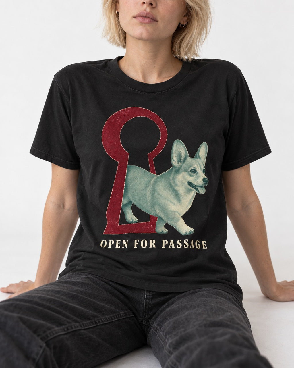 Corgi Open for Passage Keyhole Graphic T-Shirt in Black, worn by a seated model