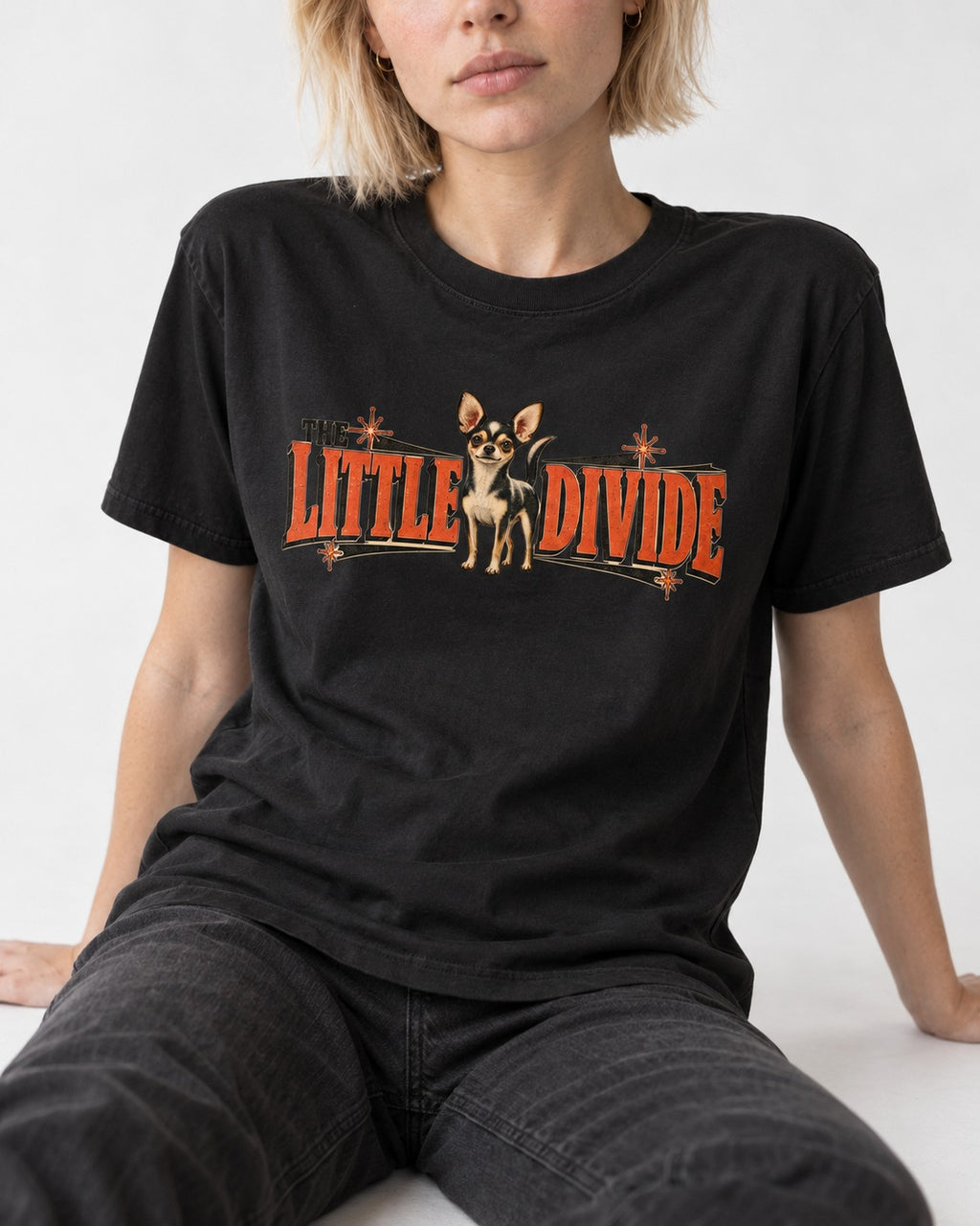 Chihuahua The Little Divide Retro Sign Graphic T-Shirt in Black, worn by a seated model