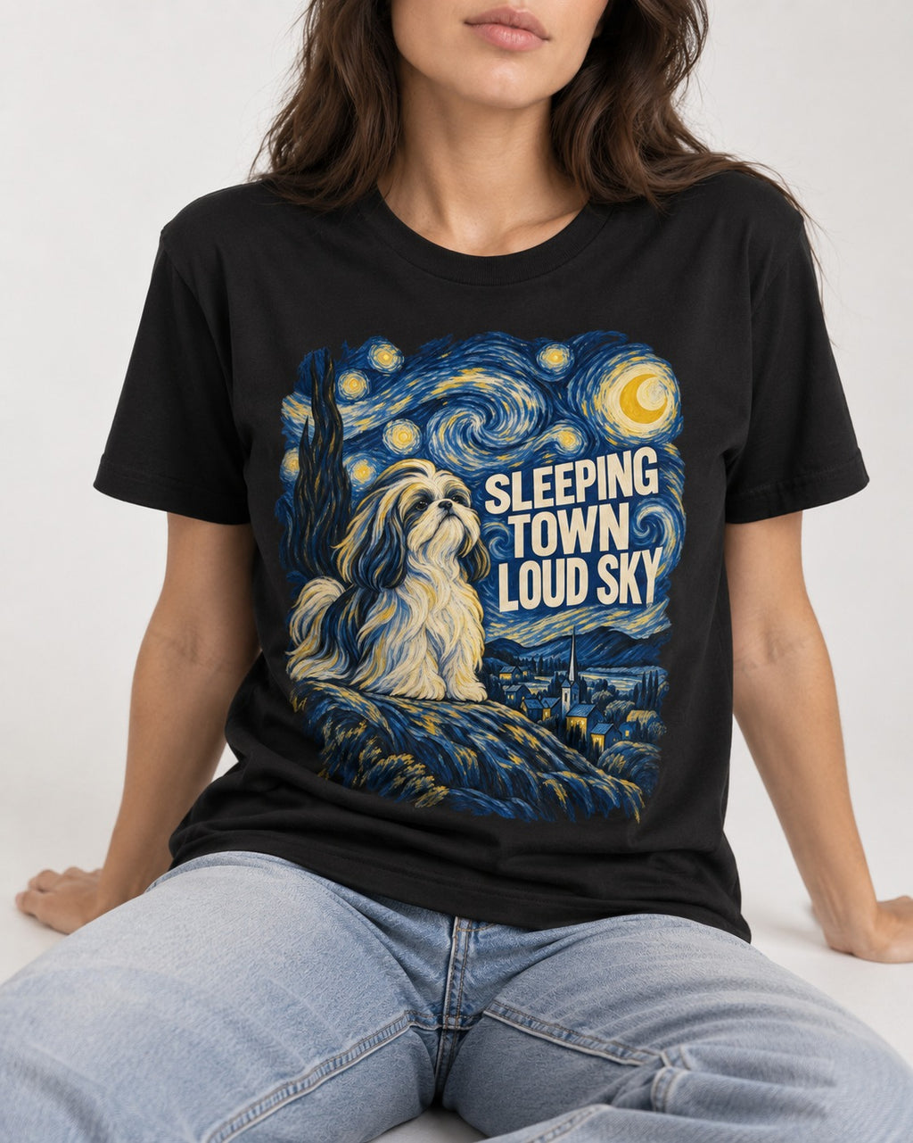 Shih Tzu Sleeping Town Loud Sky Swirling Night Graphic T-Shirt in Black, worn by a seated model
