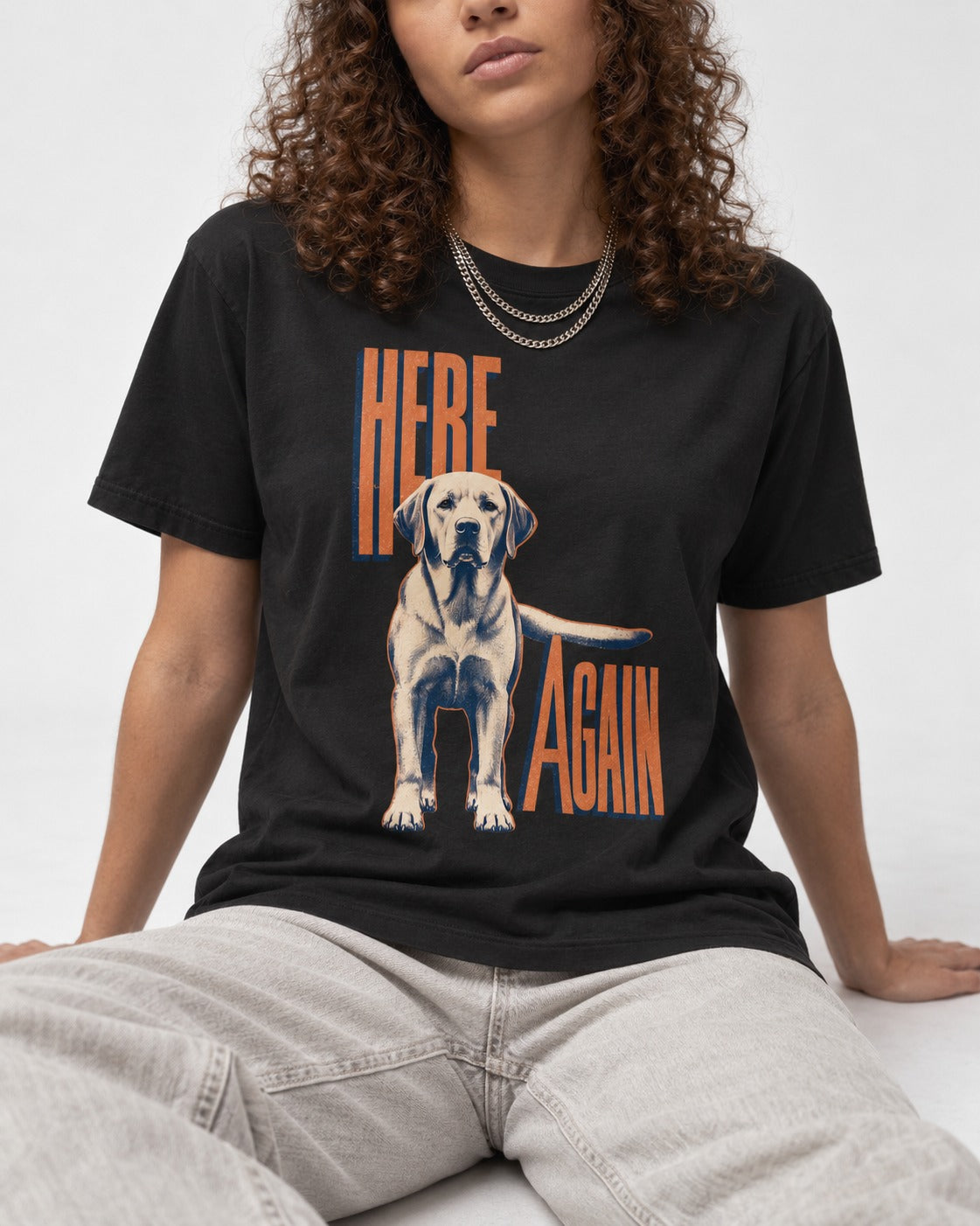 Labrador Retriever Here Again Standing Typography Graphic T-Shirt in Black, worn by a seated model