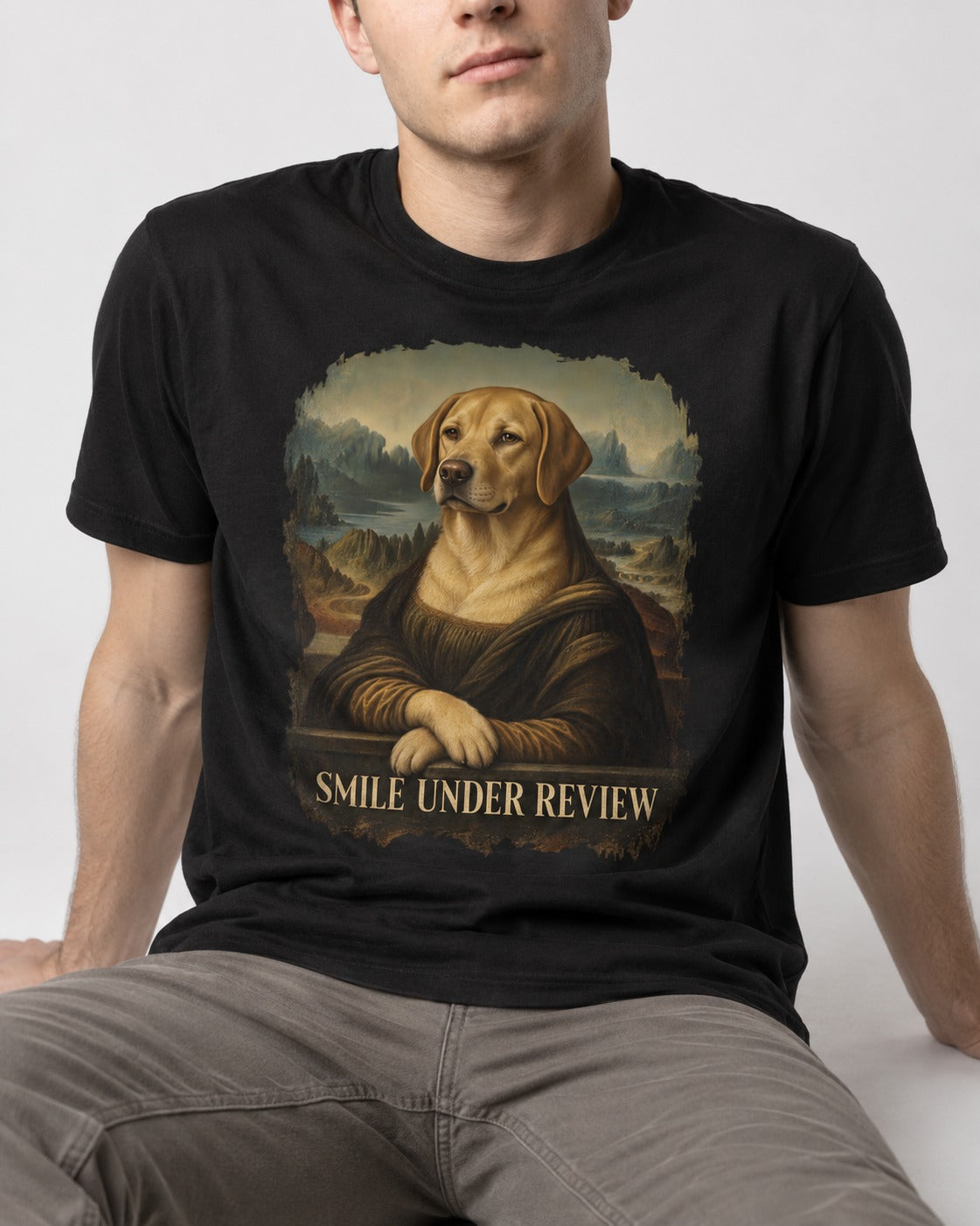Labrador Retriever Smile Under Review Mona Lisa Graphic T-Shirt in Black, worn by a seated model