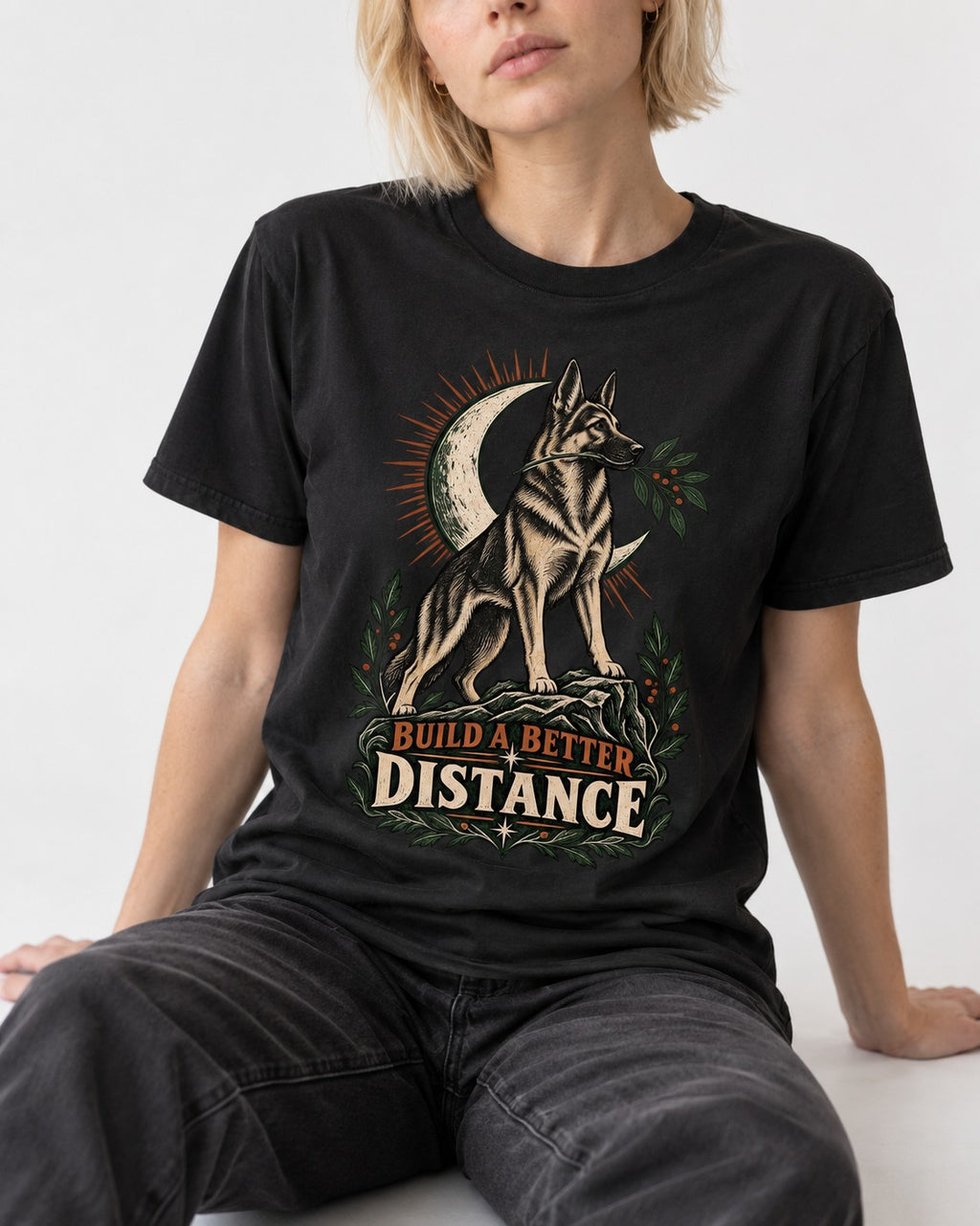 Build A Better Distance Moon Woodcut German Shepherd Dog Graphic T-Shirt in Black, worn by a seated model