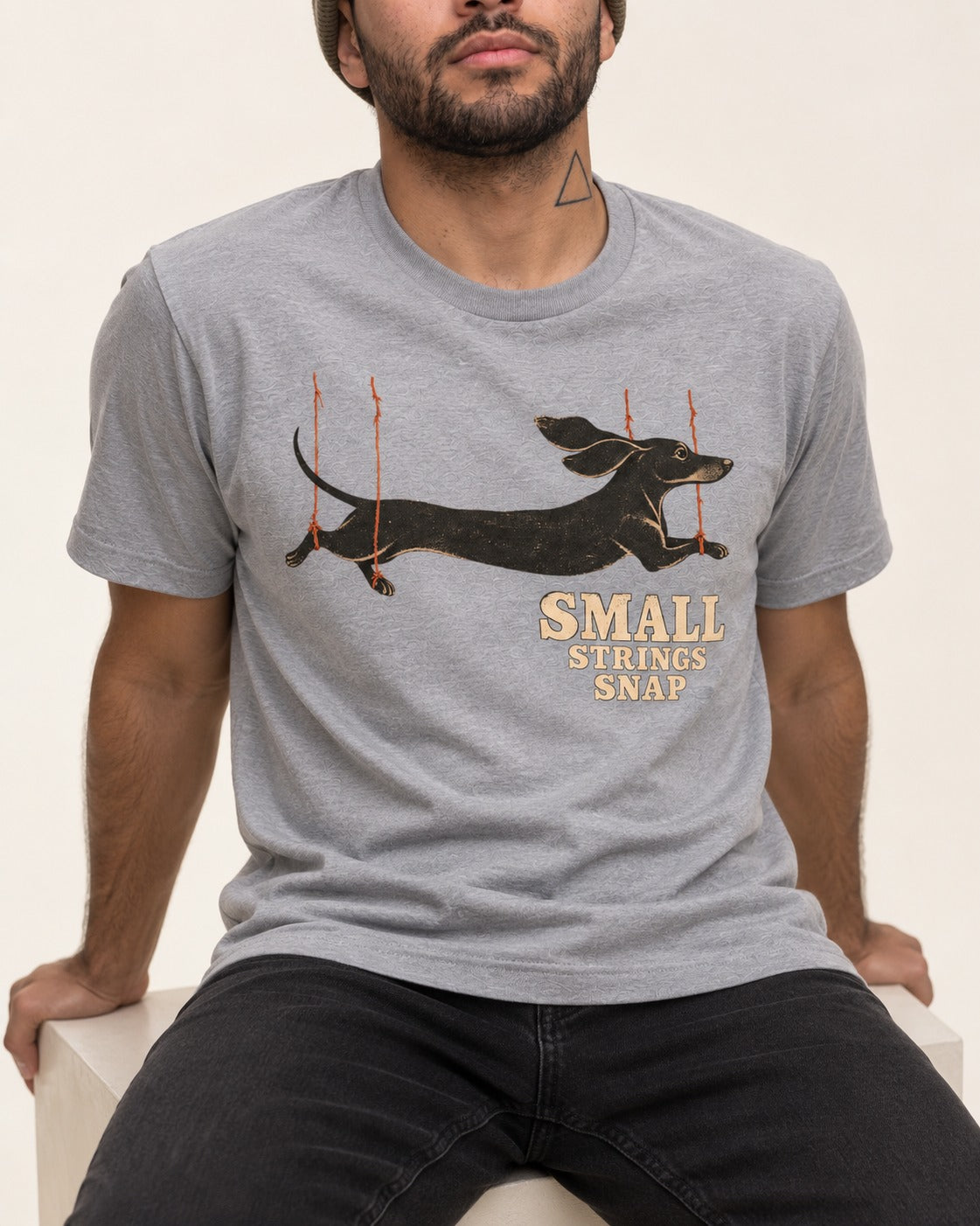 Dachshund Small Strings Snap Marionette Graphic T-Shirt in Sport Grey, worn by a seated model