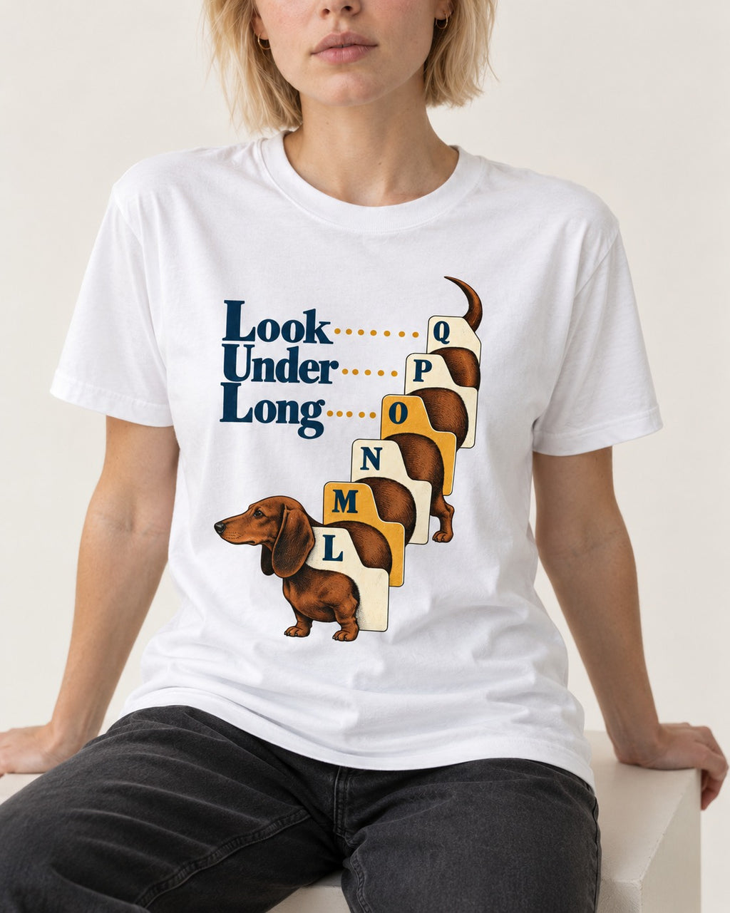 Look Under Long Dachshund T-Shirt in White, worn by a seated model