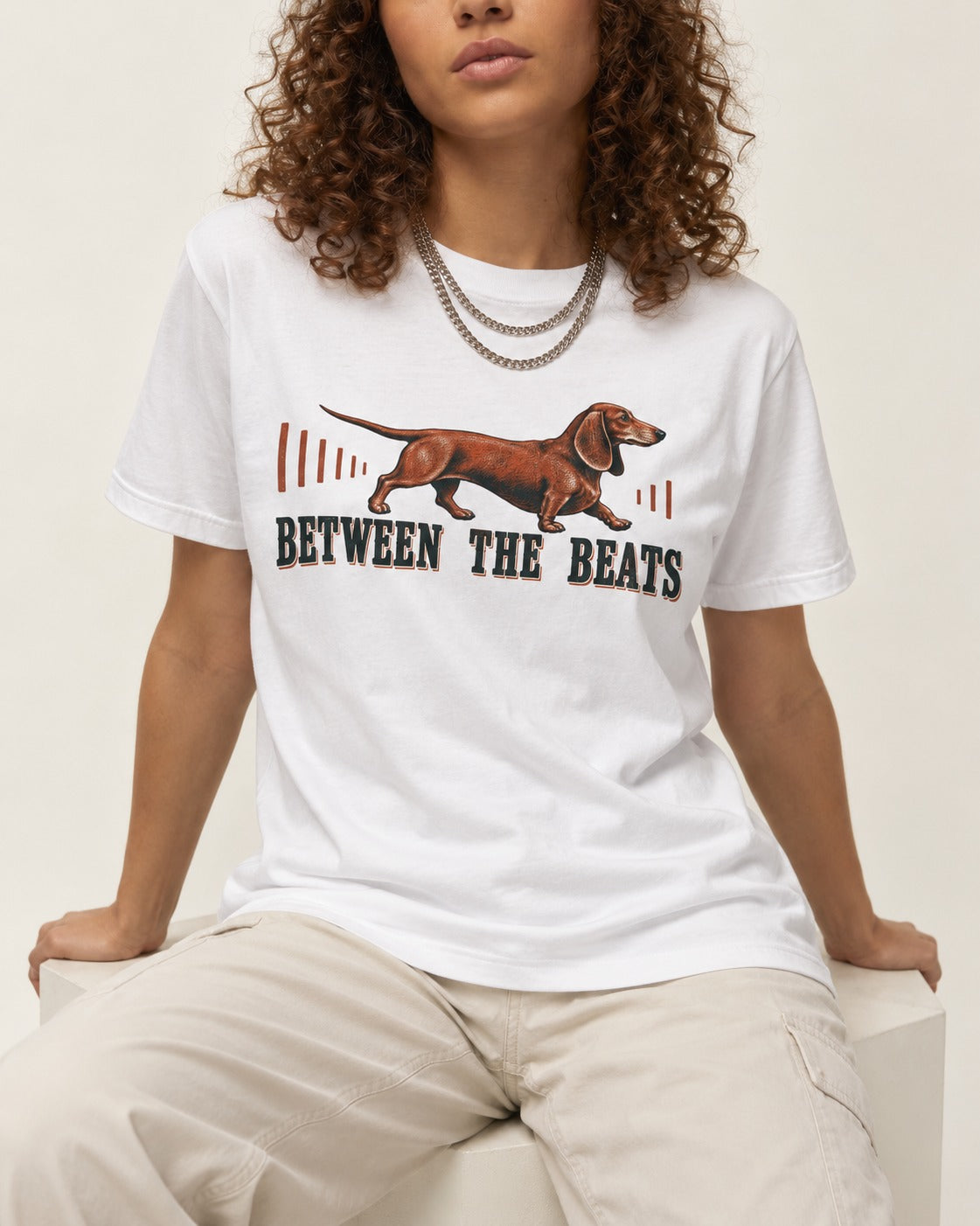 Dachshund Between the Beats T-Shirt in White, worn by a seated model