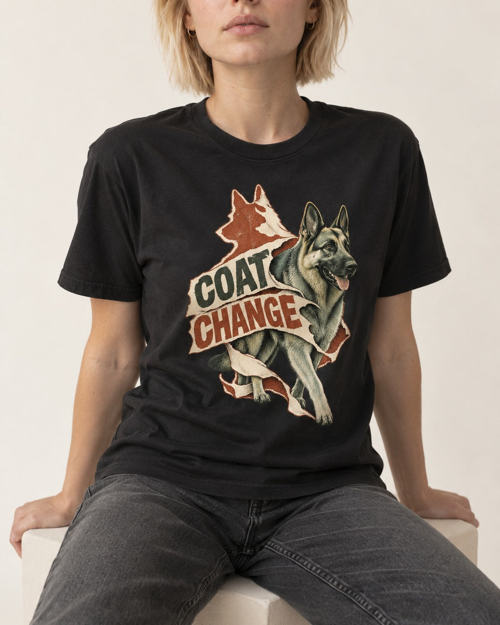 Coat Change Running German Shepherd Dog Ribbon Graphic T-Shirt in Black, worn by a seated model