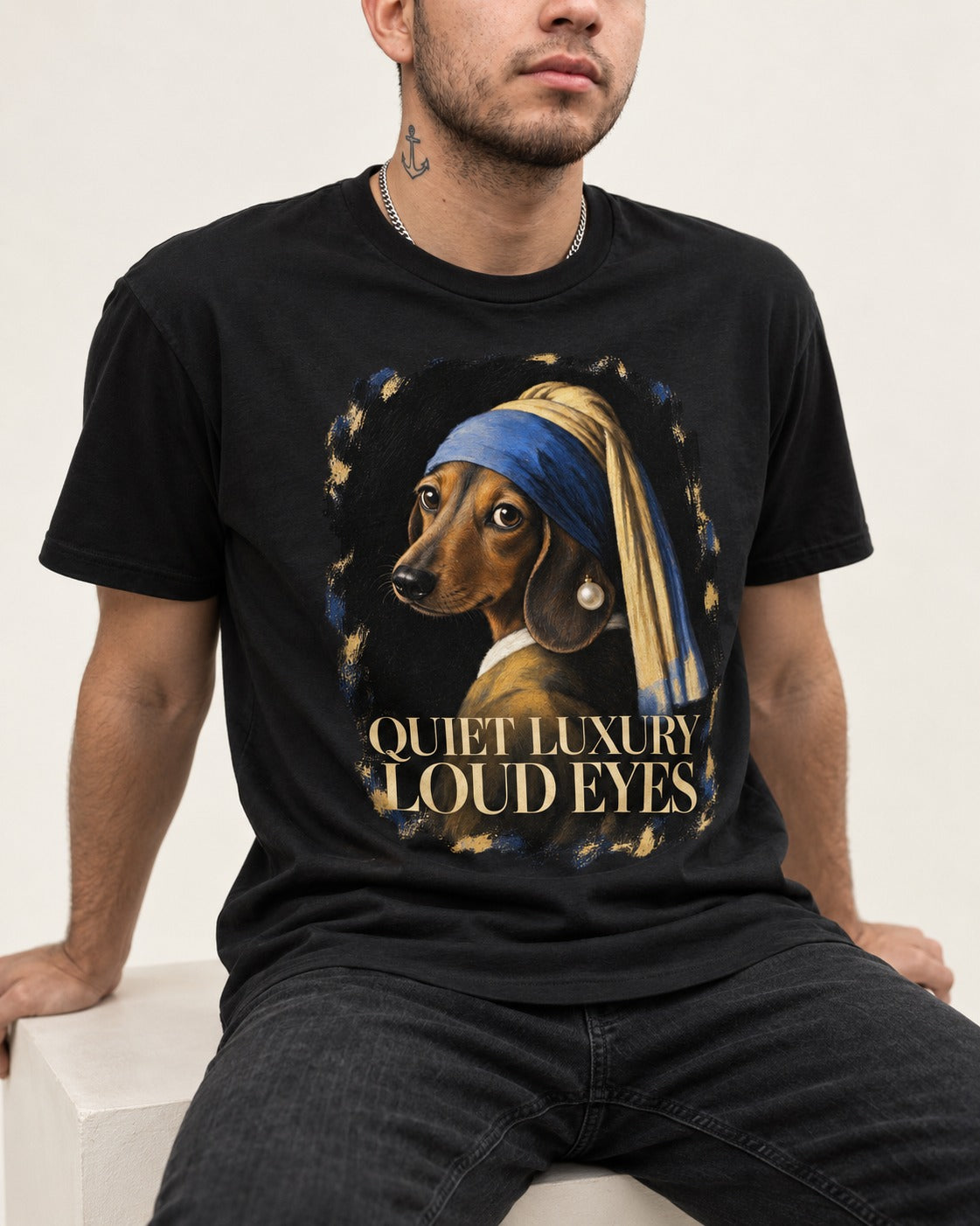 Dachshund Quiet Luxury Loud Eyes Pearl Portrait Graphic T-Shirt in Black, worn by a seated model