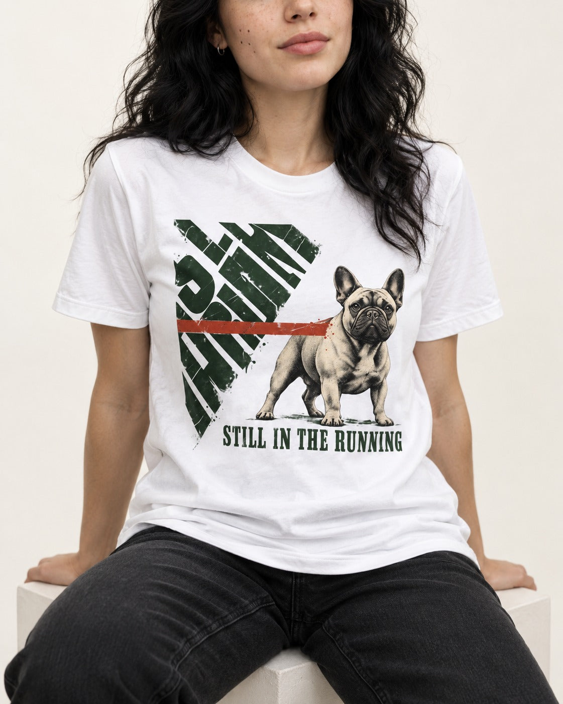 Frenchie Still in the Running T-Shirt in White, worn by a seated model