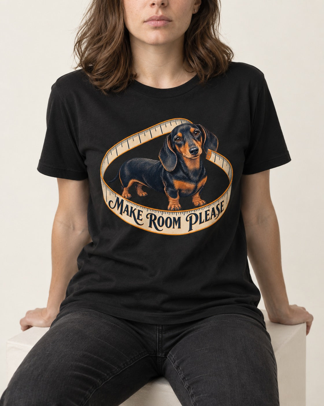 Dachshund Make Room Please Measuring Tape Graphic T-Shirt in Black, worn by a seated model