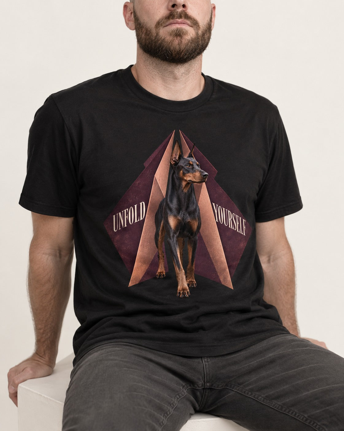 Doberman Unfold Yourself Geometric Portrait Graphic T-Shirt in Black, worn by a seated model