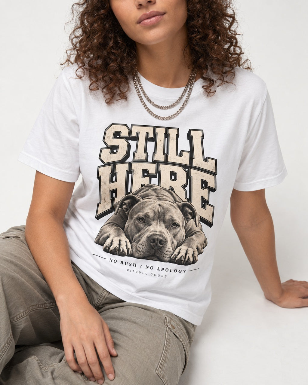 Still Here Pitbull T-Shirt in White, worn by a seated model