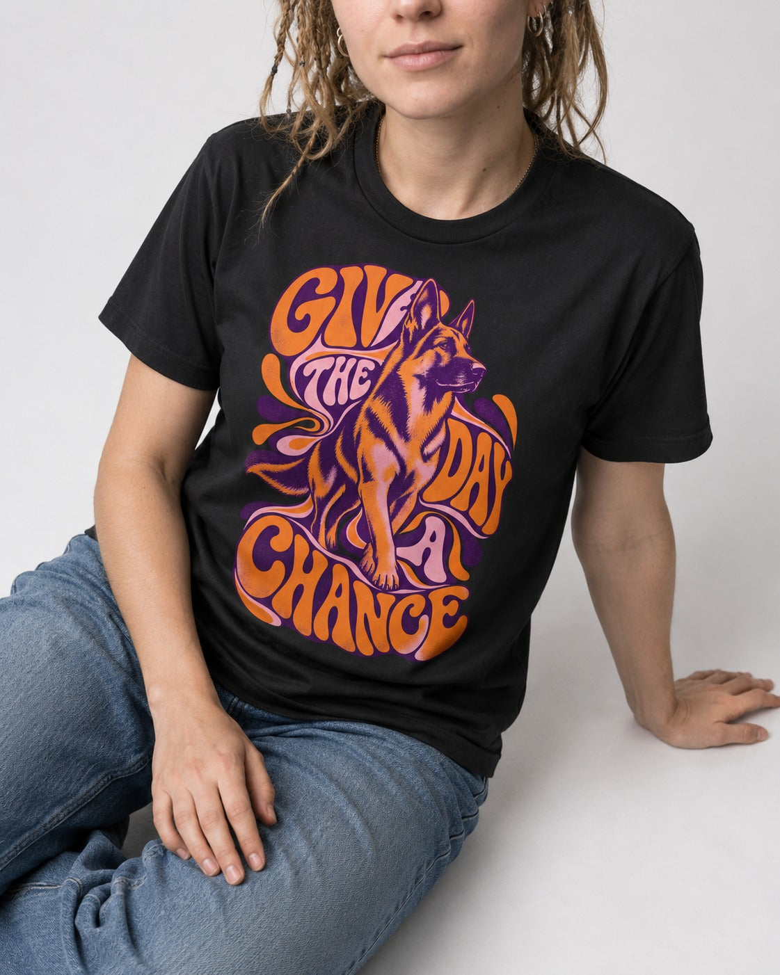Give The Day A Chance Psychedelic German Shepherd Dog Graphic T-Shirt in Black, worn by a seated model