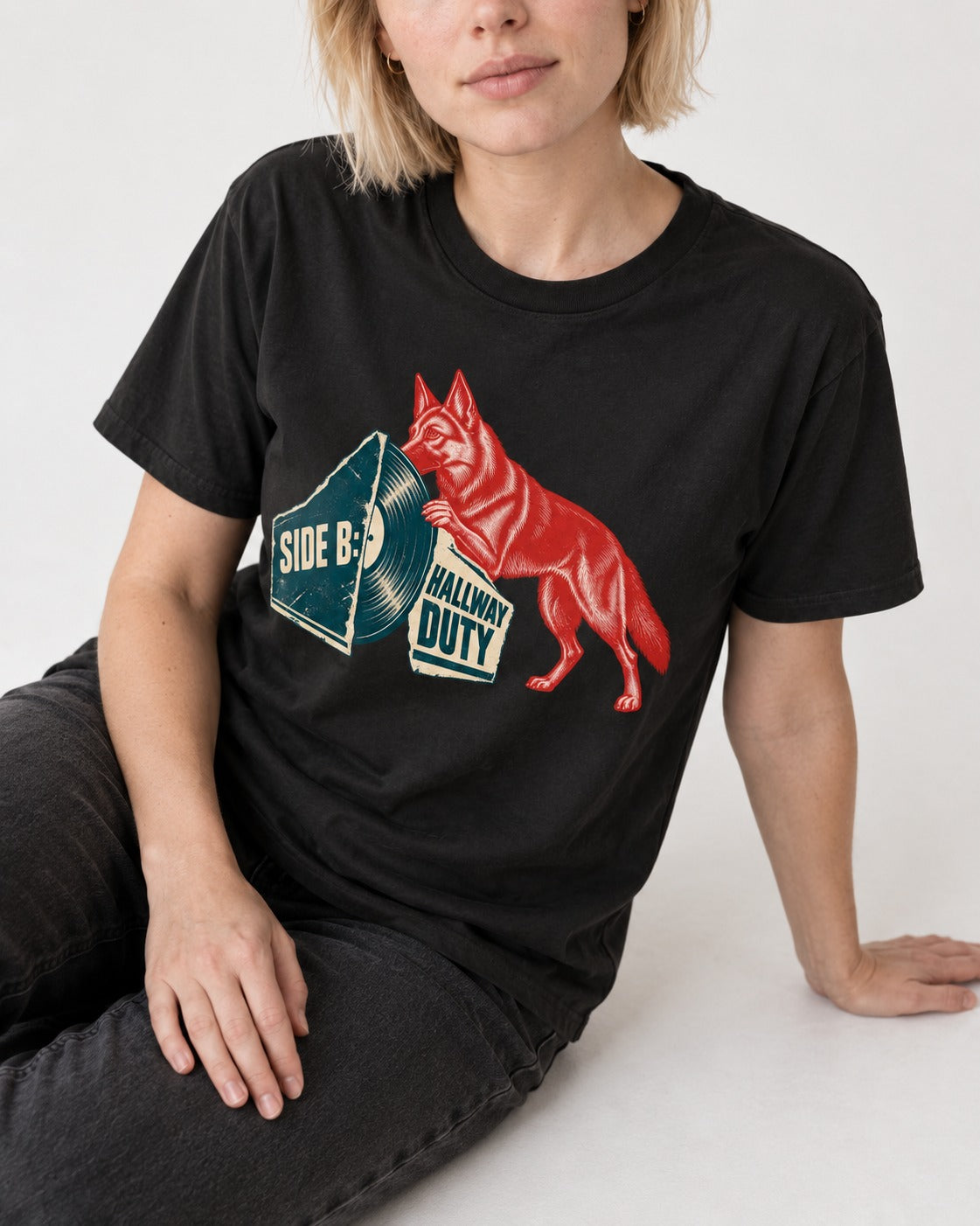 Side B Hallway Duty Vinyl Record German Shepherd Dog Graphic T-Shirt in Black, worn by a seated model