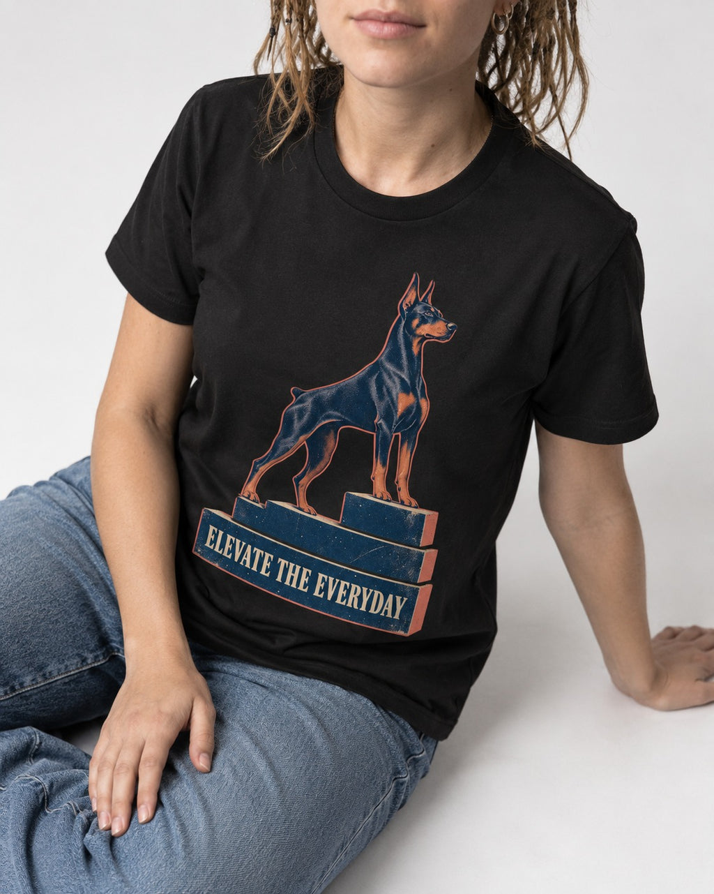 Doberman Elevate the Everyday Podium Graphic T-Shirt in Black, worn by a seated model