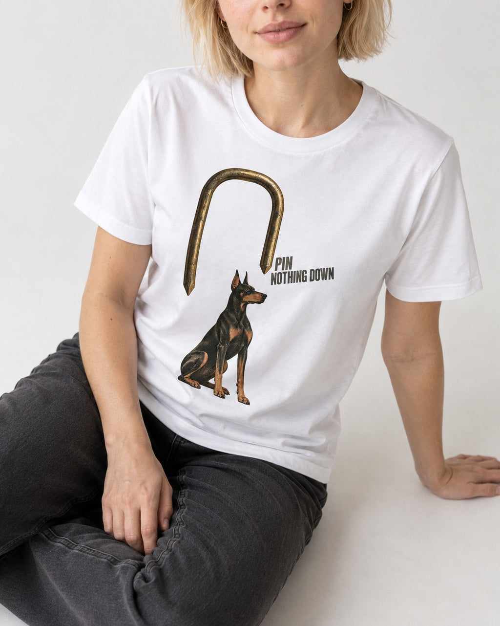 Nothing Pins Doberman Down T-Shirt in White, worn by a seated model