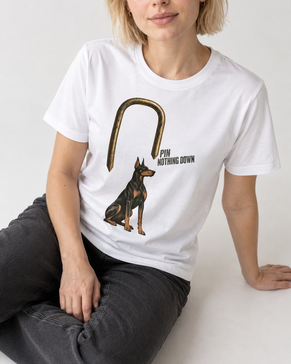 Nothing Pins Doberman Down T-Shirt in White, worn by a seated model