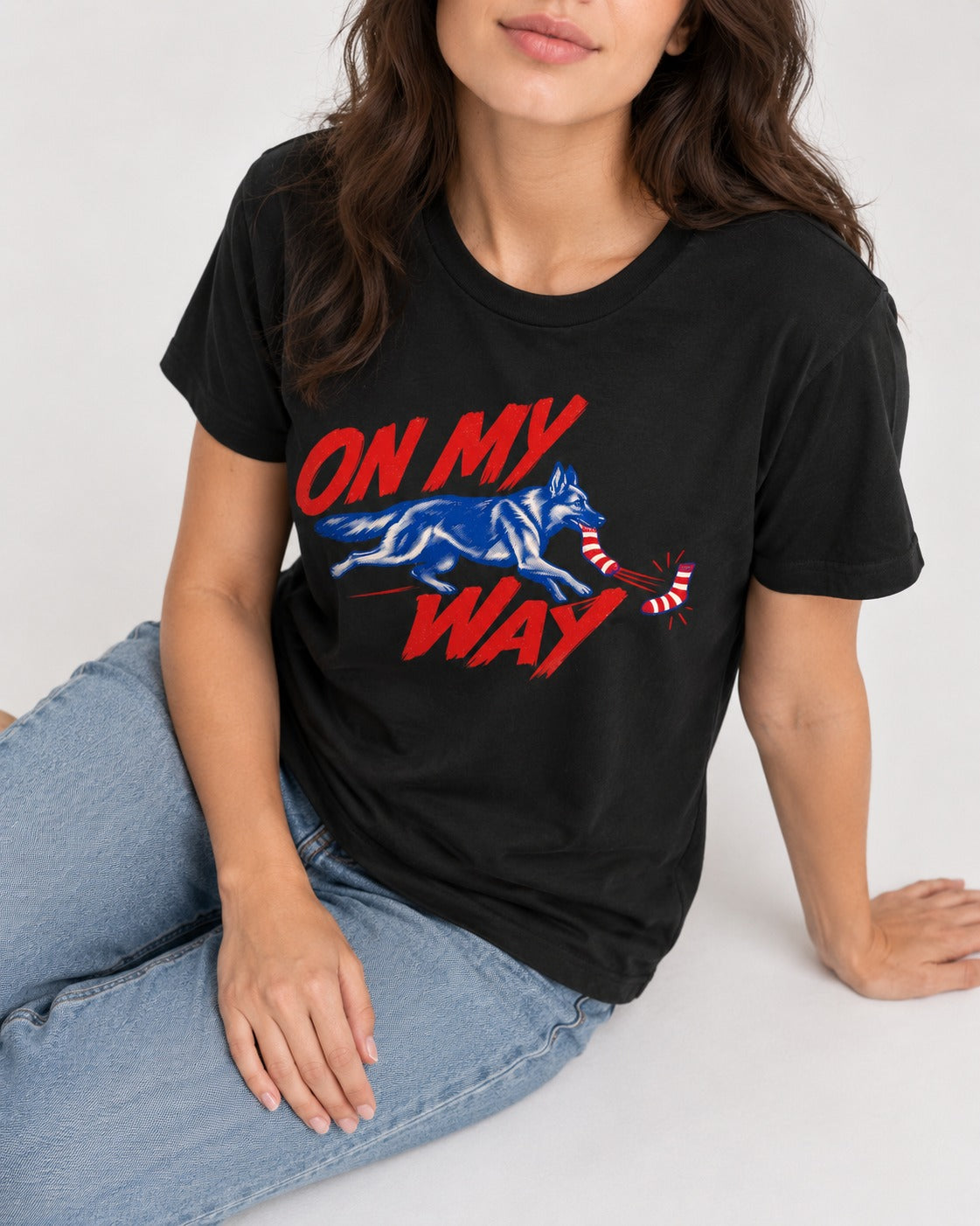 German Shepherd Dog On My Way Sock Chase Graphic T-Shirt in Black, worn by a seated model