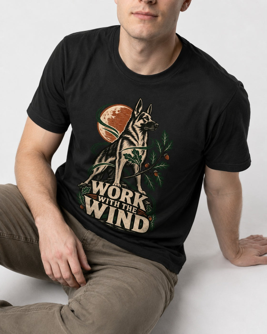 Work With The Wind Botanical Woodcut German Shepherd Dog Graphic T-Shirt in Black, worn by a seated model