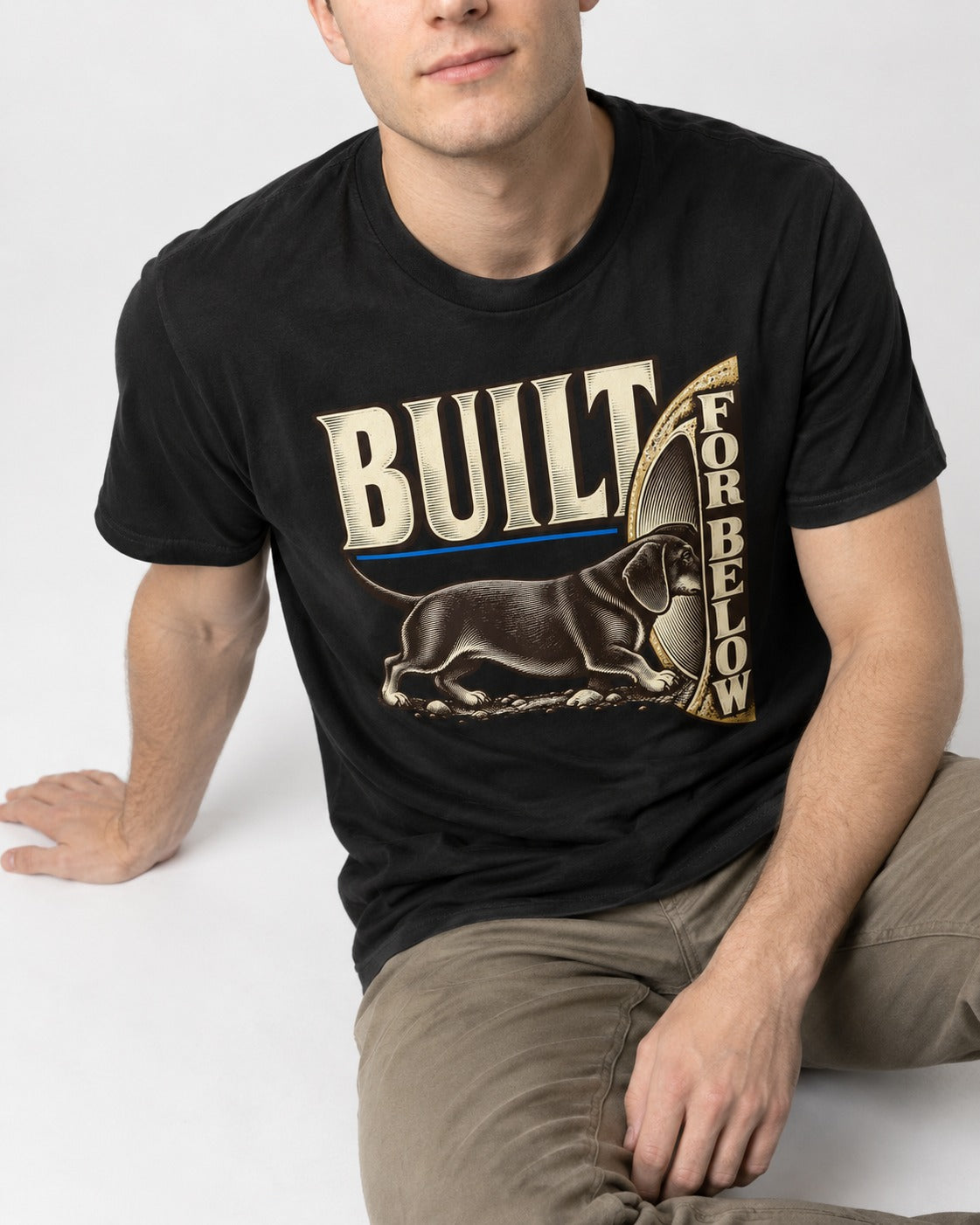 Dachshund Built for Below Vintage Burrow Graphic T-Shirt in Black, worn by a seated model