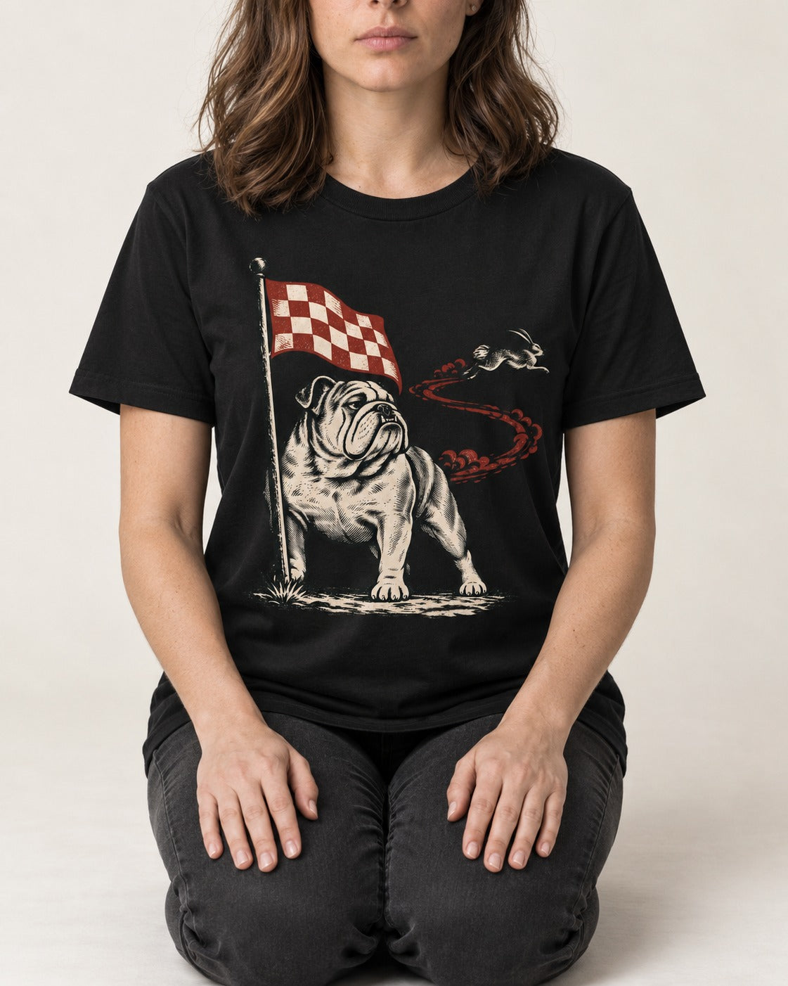 English Bulldog Checkered Flag Rabbit Chase T-Shirt in Black, worn by a seated model