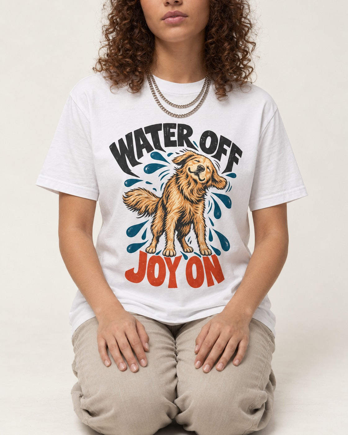 Water Off Joy on Golden Retriever T-Shirt in White, worn by a seated model