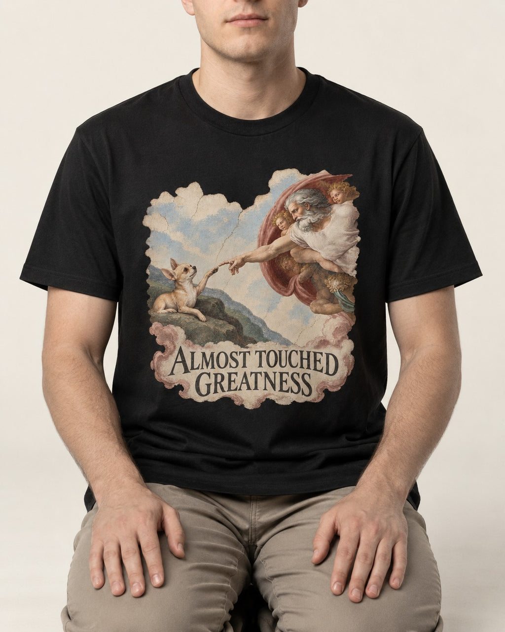 Chihuahua Almost Touched Greatness Renaissance Parody T-Shirt in Black, worn by a seated model