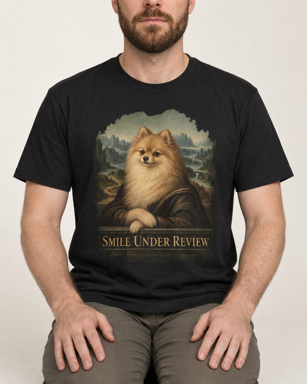 Pomeranian Smile Under Review Renaissance Portrait Graphic T-Shirt in Black, worn by a seated model