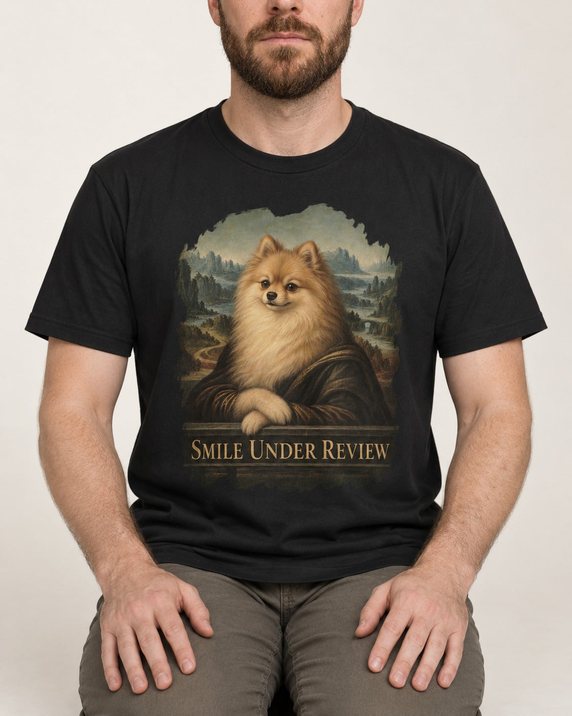 Pomeranian Smile Under Review Renaissance Portrait Graphic T-Shirt in Black, worn by a seated model
