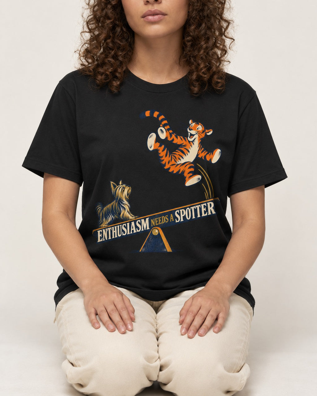 Yorkshire Terrier Enthusiasm Needs a Spotter Seesaw Graphic T-Shirt in Black, worn by a seated model