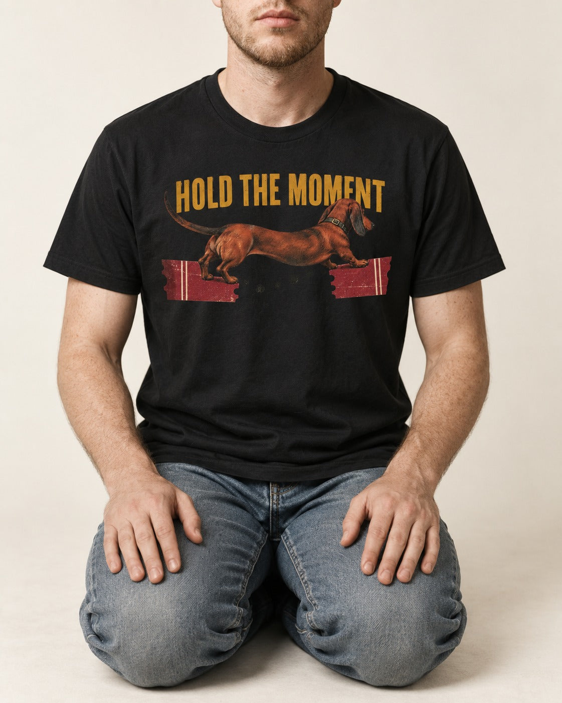 Dachshund Hold The Moment Torn Ticket Bridge Graphic T-Shirt in Black, worn by a seated model