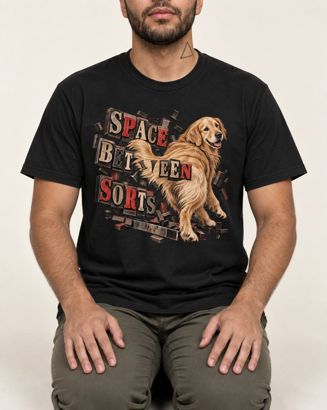 Golden Retriever Space Between Sorts Letterpress Graphic T-Shirt in Black, worn by a seated model