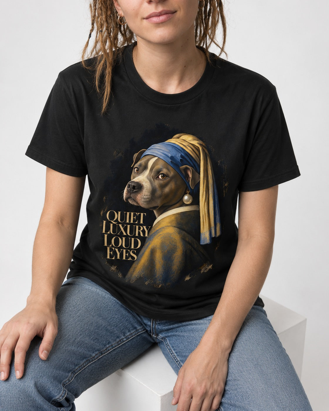 Pitbull Quiet Luxury Loud Eyes Pearl Earring Portrait Graphic T-Shirt in Black, worn by a seated model
