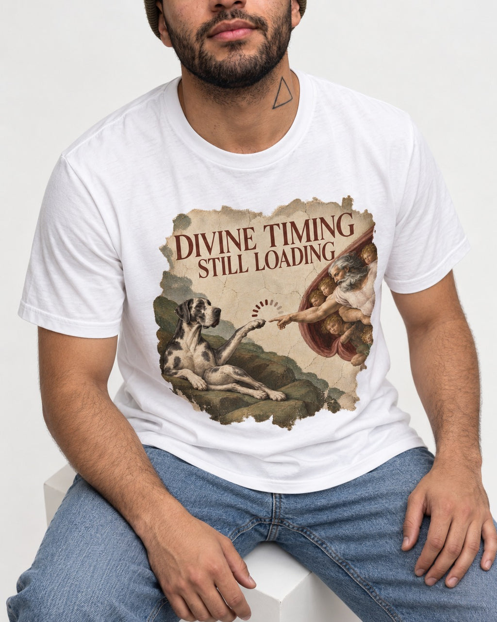 Great Dane Divine Timing Still Loading T-Shirt in White, worn by a seated model
