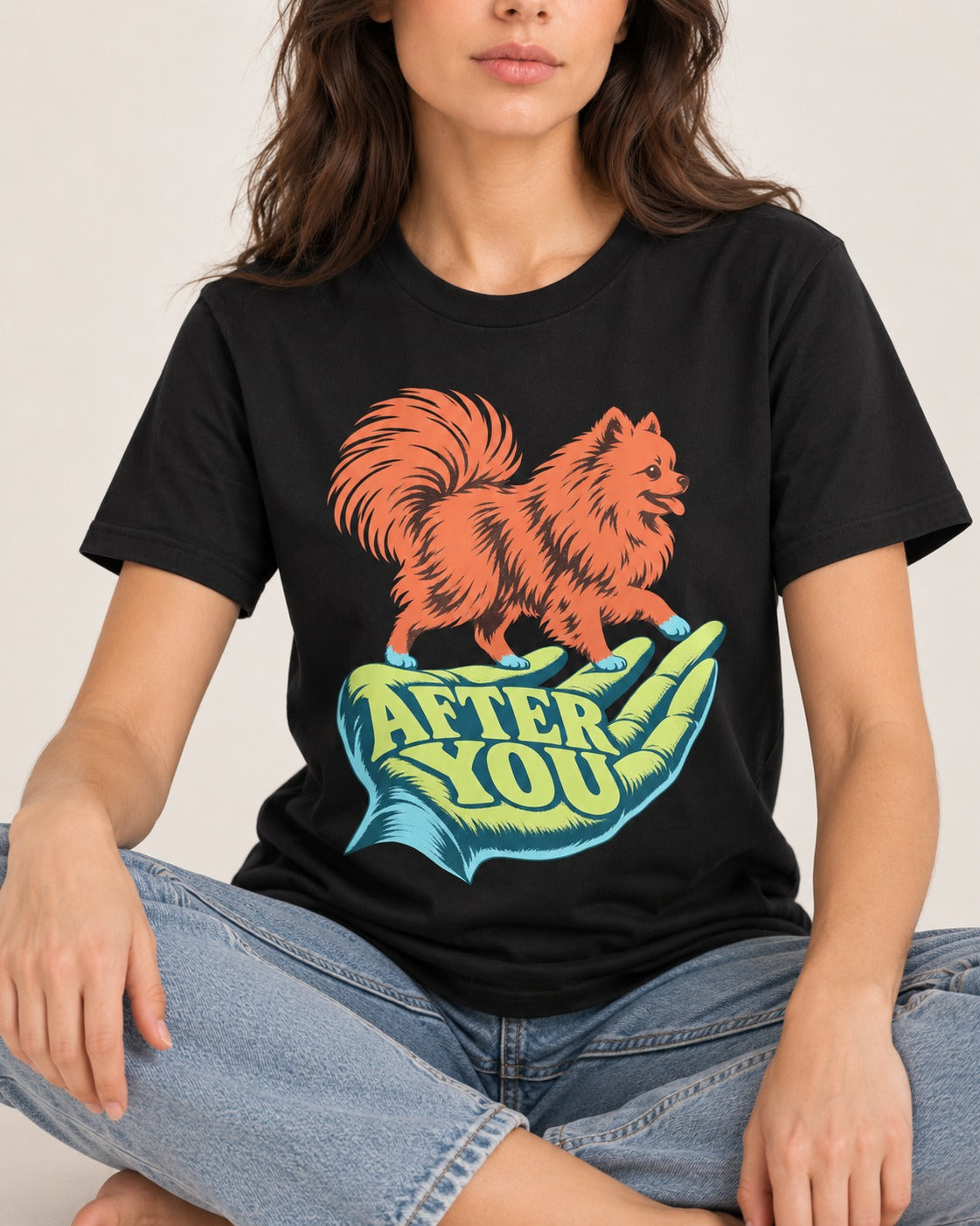 Pomeranian After You Helping Hand Graphic T-Shirt in Black, worn by a seated model