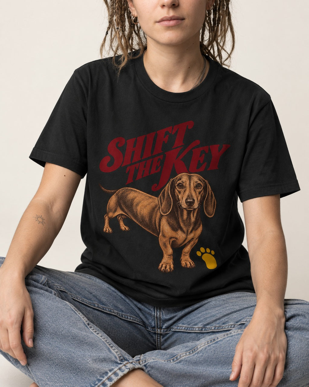Dachshund Shift The Key Pawprint Graphic T-Shirt in Black, worn by a seated model