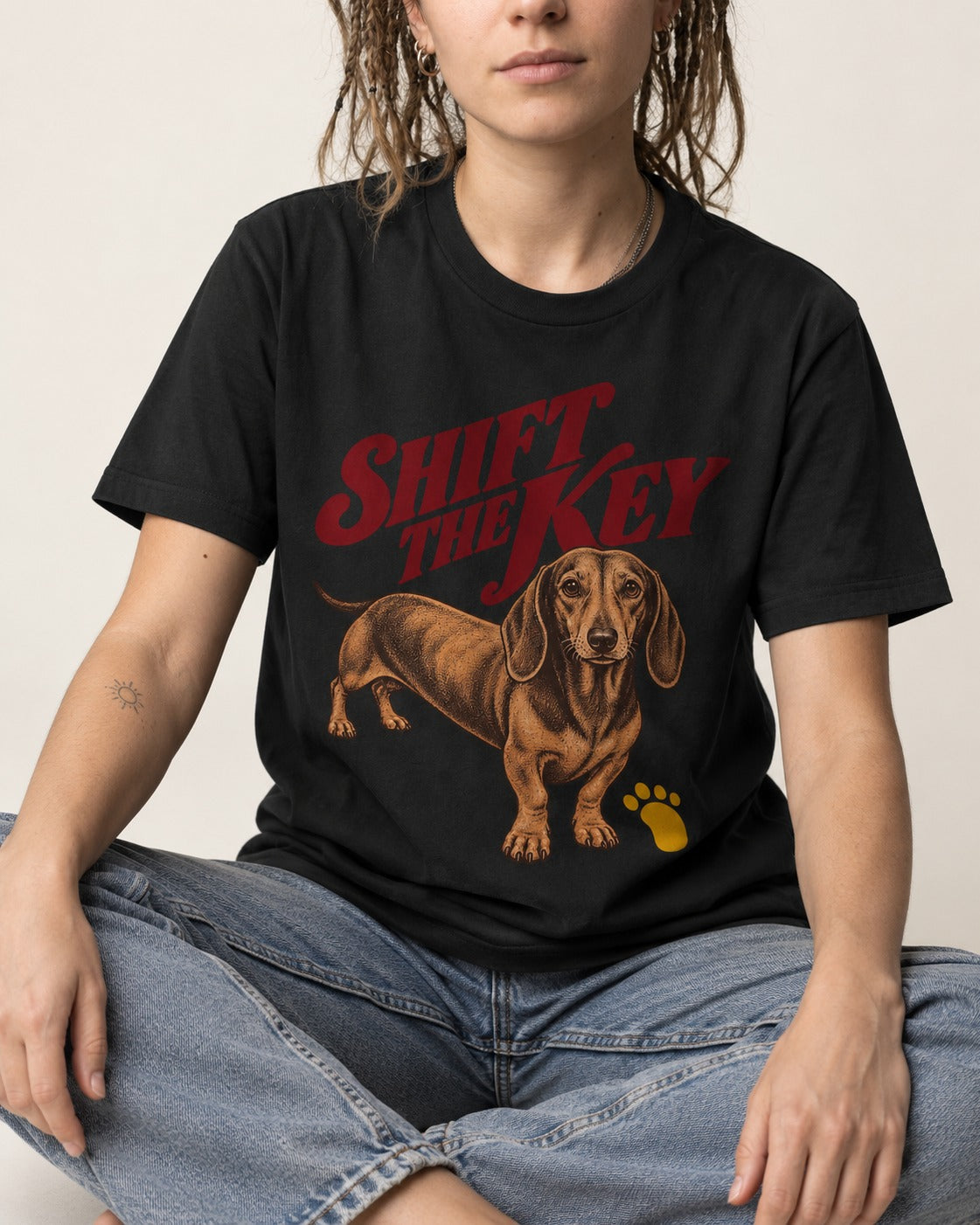 Dachshund Shift The Key Pawprint Graphic T-Shirt in Black, worn by a seated model