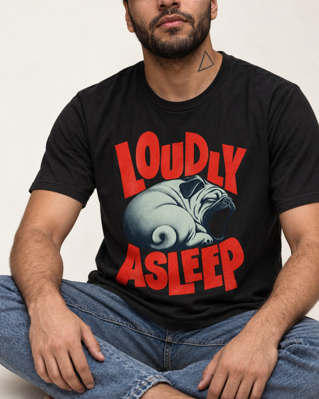 Pug Loudly Asleep Curled Yawn Graphic T-Shirt in Black, worn by a seated model