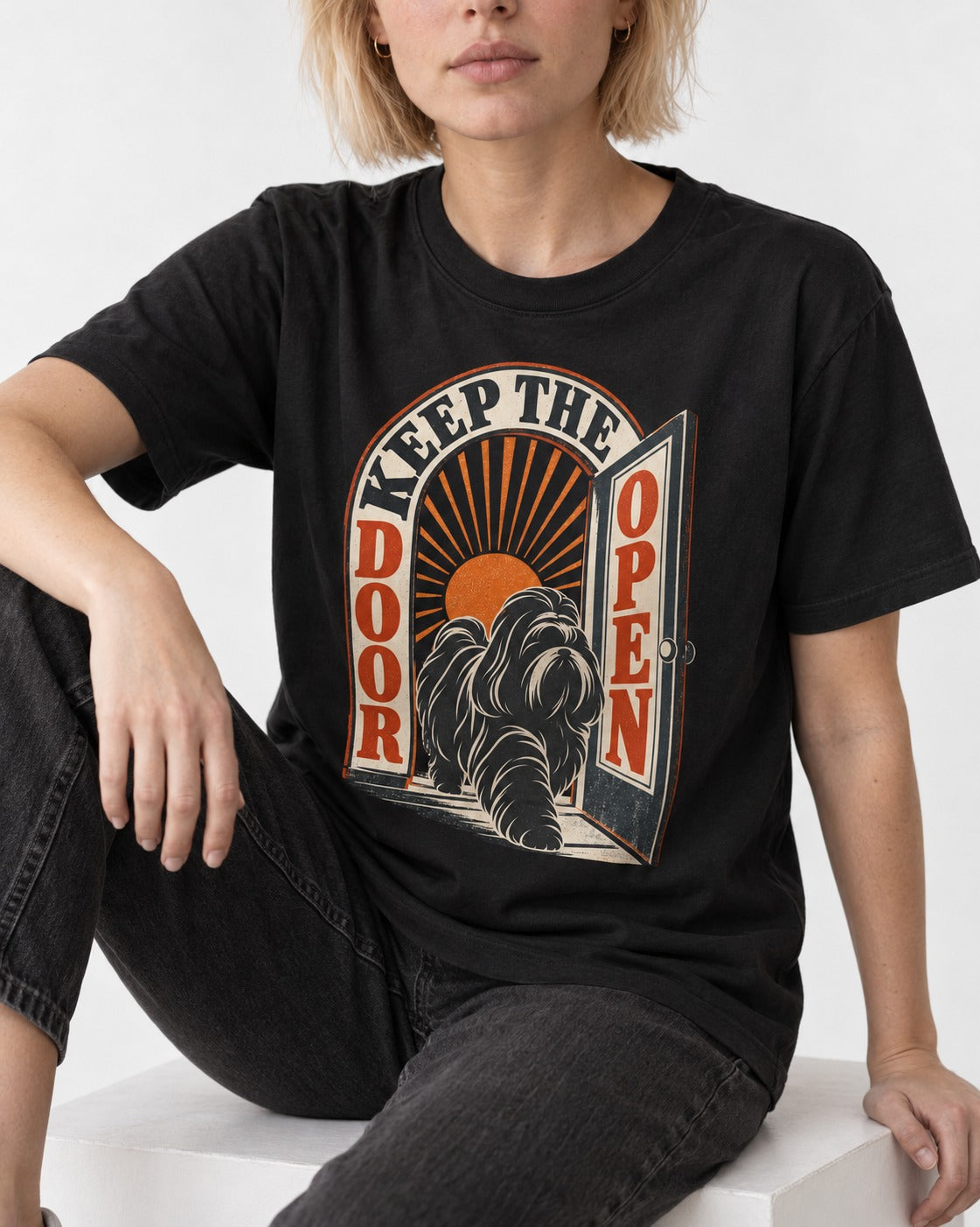 Shih Tzu Keep the Door Open Retro Doorway Graphic T-Shirt in Black, worn by a seated model