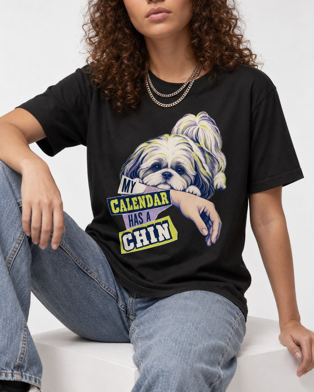 Shih Tzu My Calendar Has a Chin Arm Rest Graphic T-Shirt in Black, worn by a seated model