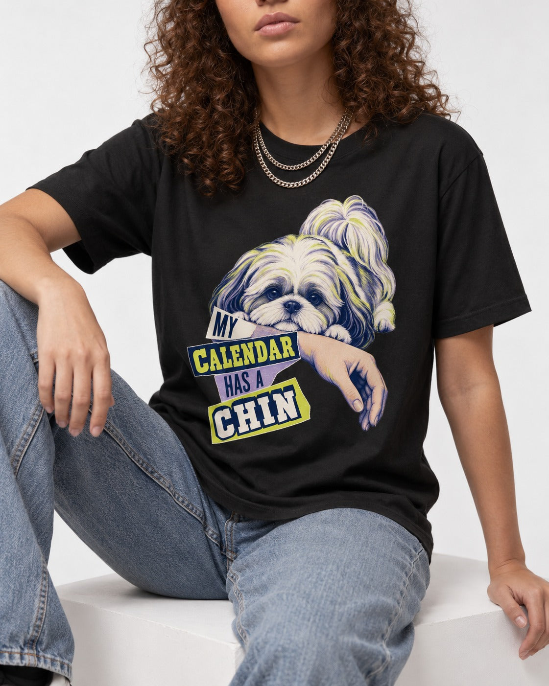 Shih Tzu My Calendar Has a Chin Arm Rest Graphic T-Shirt in Black, worn by a seated model