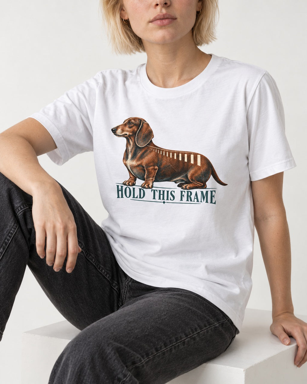 Dachshund Hold This Frame T-Shirt in White, worn by a seated model