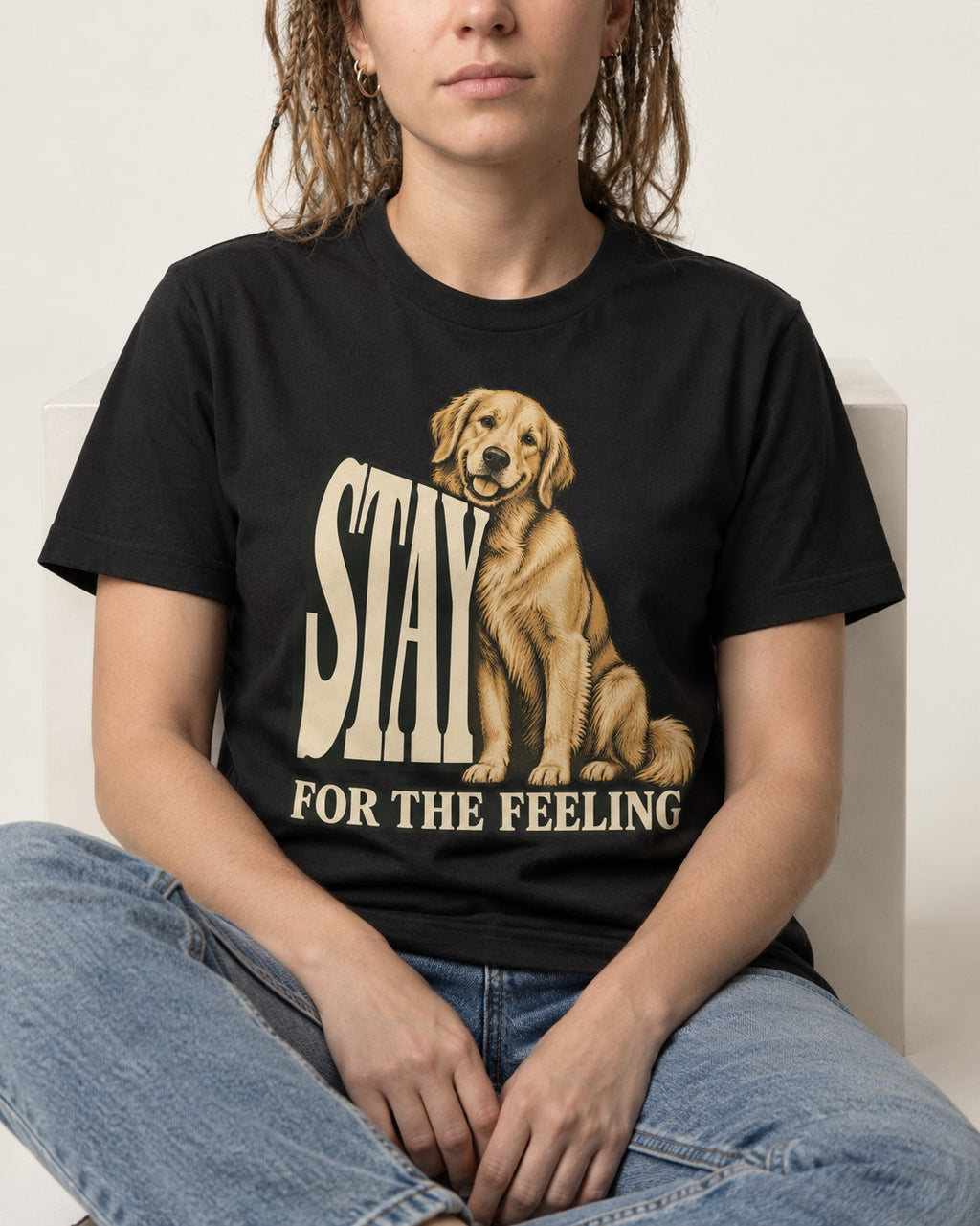 Golden Retriever Stay for the Feeling Leaning Puppy Graphic T-Shirt in Black, worn by a seated model