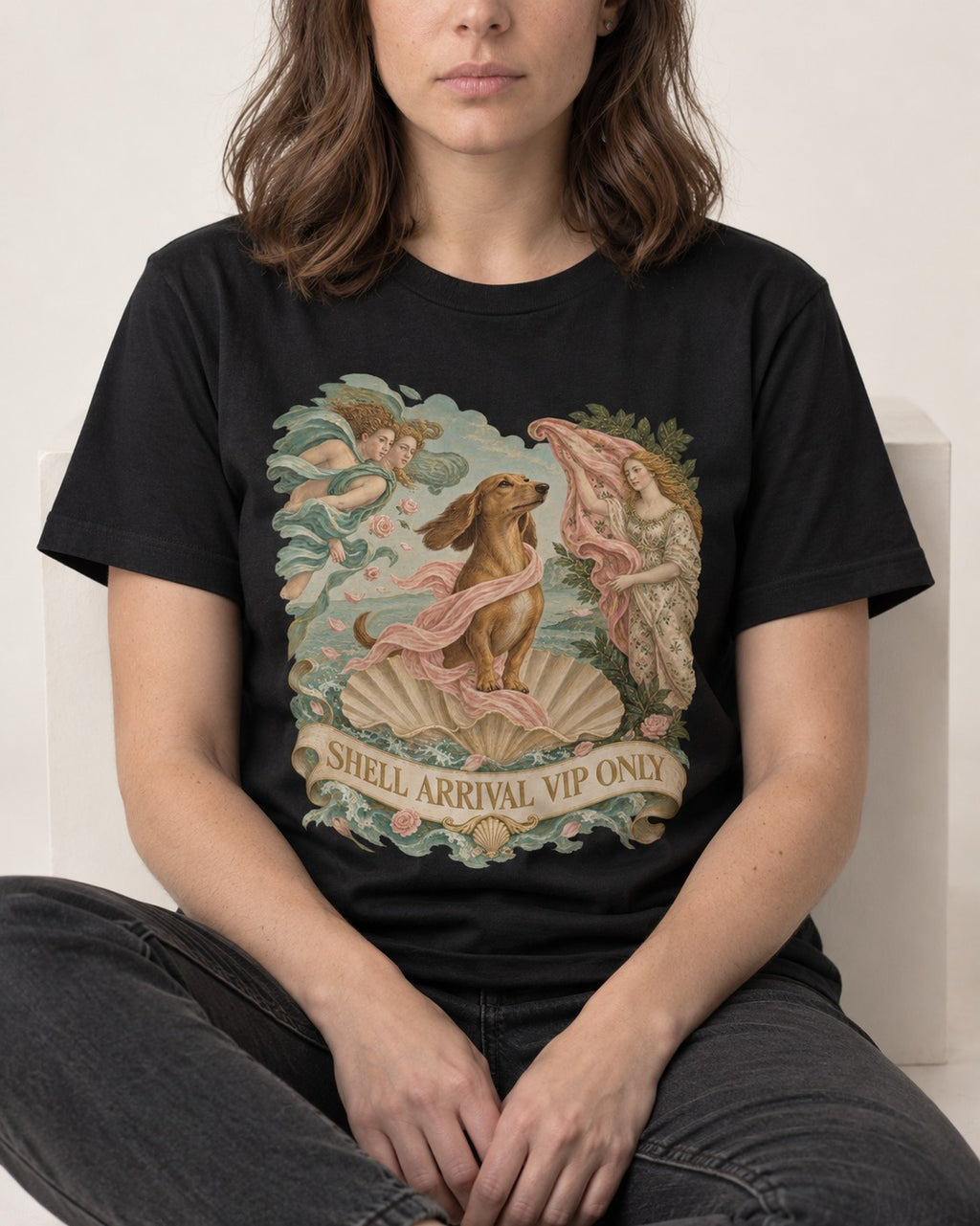 Dachshund Shell Arrival VIP Only Venus Parody Graphic T-Shirt in Black, worn by a seated model