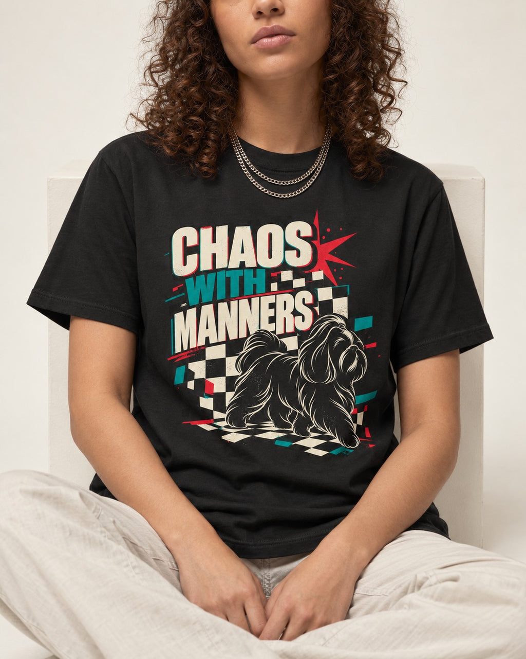 Shih Tzu Chaos with Manners Checkerboard Graphic T-Shirt in Black, worn by a seated model