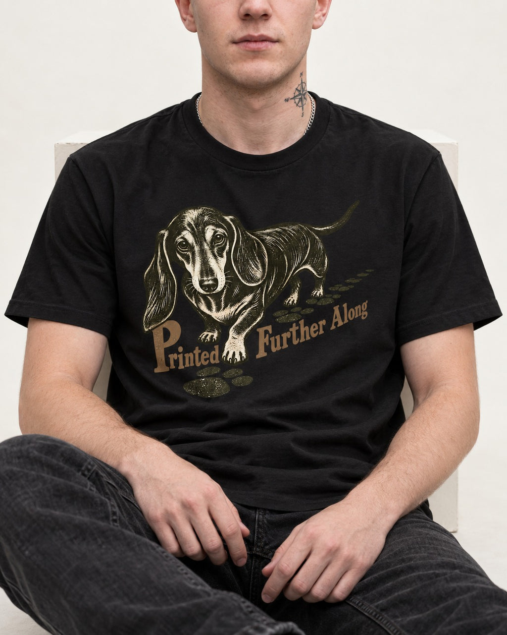 Dachshund Printed Further Along Footprint Graphic T-Shirt in Black, worn by a seated model