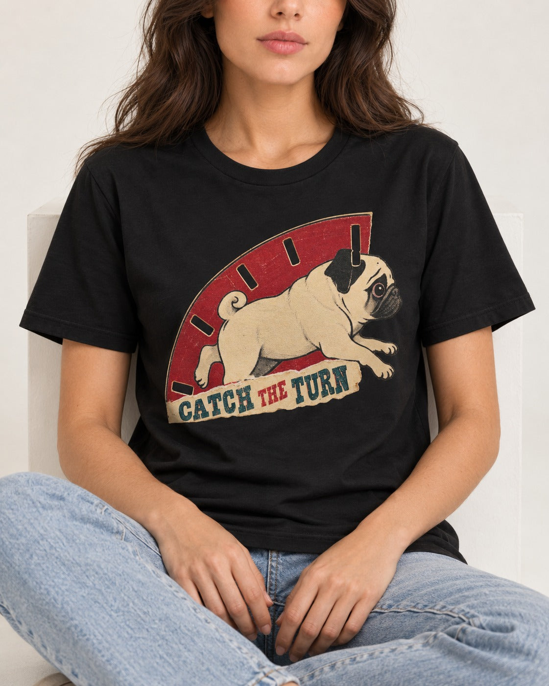 Pug Catch the Turn Track Graphic T-Shirt in Black, worn by a seated model