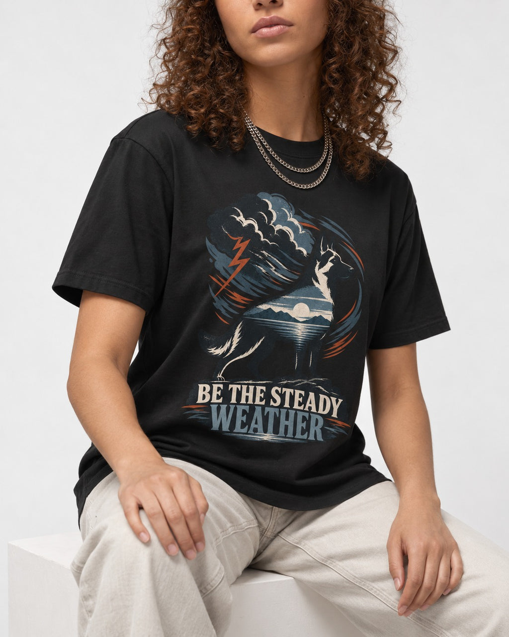 Be the Steady Weather Storm German Shepherd Dog Graphic T-Shirt in Black, worn by a seated model