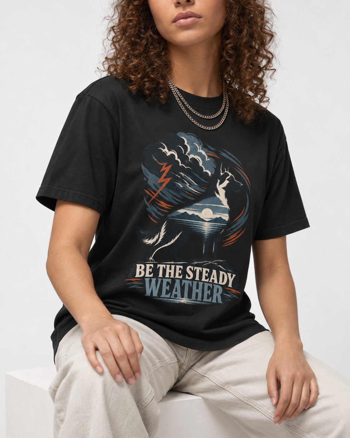 Be the Steady Weather Storm German Shepherd Dog Graphic T-Shirt in Black, worn by a seated model